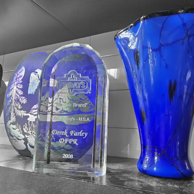 A blue vase sitting next to two awards.