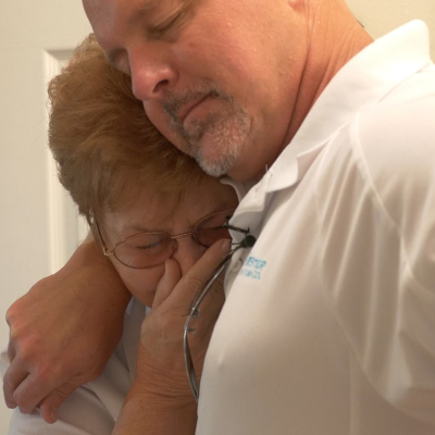 A man and woman hugging in the bathroom.